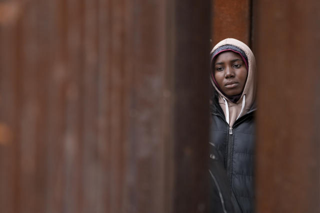 A woman looks on as she waits between two border walls to apply for asylum Friday, May 12, 2023, in San Diego. The border between the U.S. and Mexico was relatively calm Friday, offering few signs of the chaos that had been feared following a rush by worried migrants to enter the U.S. before the end of pandemic-related immigration restrictions. (AP Photo/Gregory Bull)