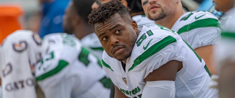 Brandon Copeland sits on the bench wearing his NFL uniform, leaning over