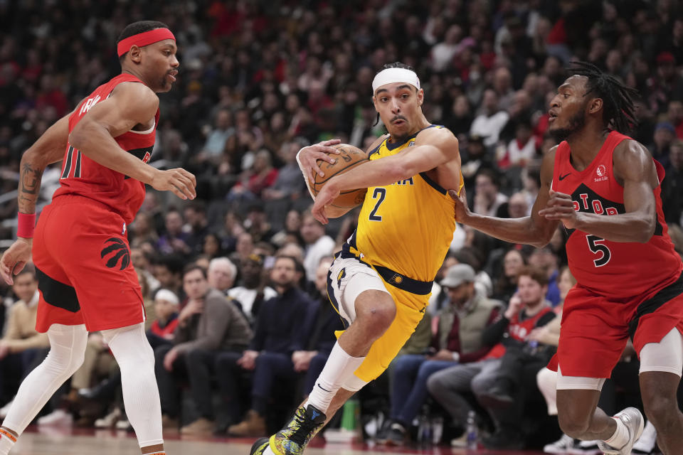 Indiana Pacers' Andrew Nembhard, centre, drives between Toronto Raptors' Bruce Brown, left, and Immanuel Quickley during the second half of an NBA basketball game Wednesday, Feb. 14, 2024, in Toronto. (Chris Young/The Canadian Press via AP)
