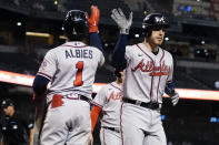 Atlanta Braves' Freddie Freeman high fives Ozzie Albies (1) after hitting a two run home run during the ninth inning of a baseball game, Wednesday, Sept. 22, 2021, in Phoenix. (AP Photo/Matt York)