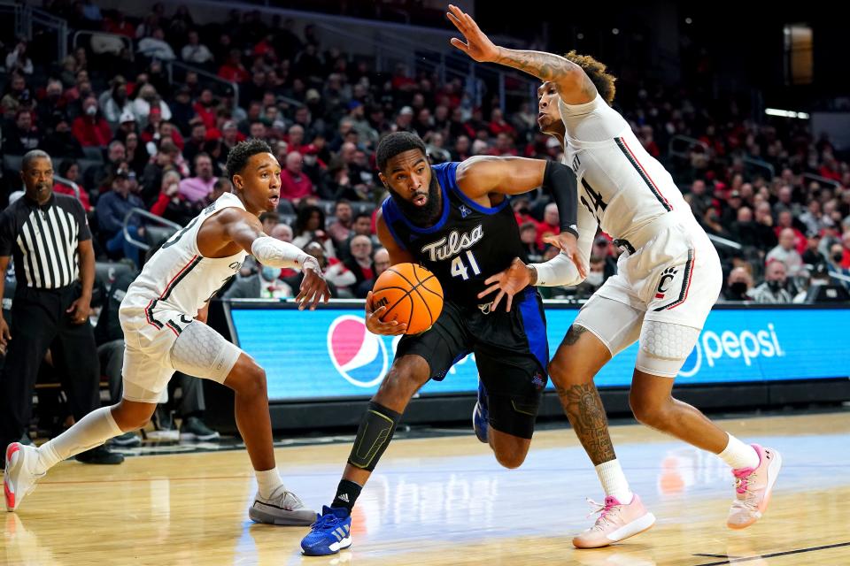 Tulsa Golden Hurricane forward Jeriah Horne (41) drives to the basket as Cincinnati Bearcats guard Mika Adams-Woods (23), left, and Cincinnati Bearcats guard Jeremiah Davenport (24), right, defend in the first half of an NCAA men's college basketball game, Thursday, Jan. 20, 2022, at Fifth Third Arena in Cincinnati.