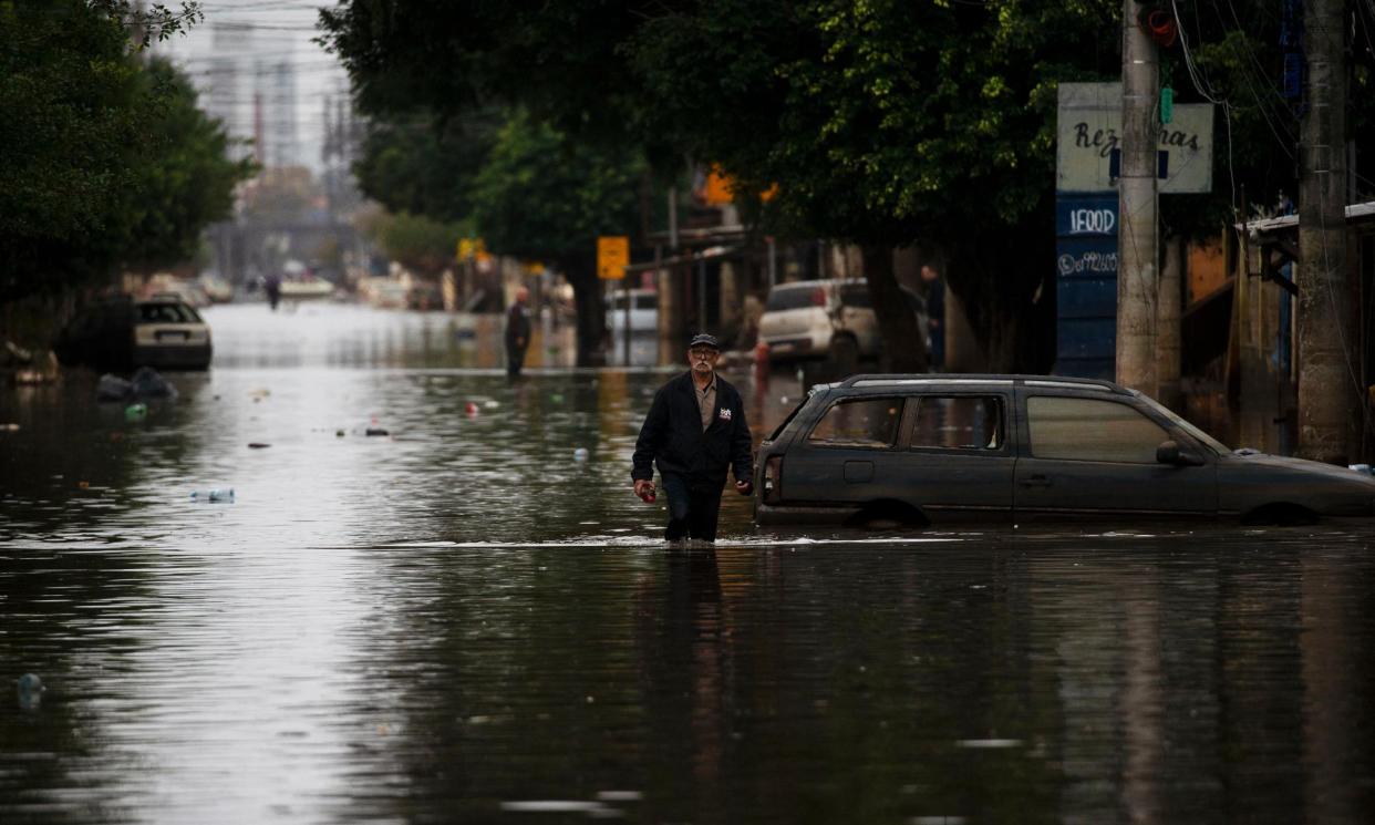 <span>A man walks through a flooded street in Porto Alegre, Brazil.</span><span>Photograph: Sílvio Ávila/AFP/Getty Images</span>