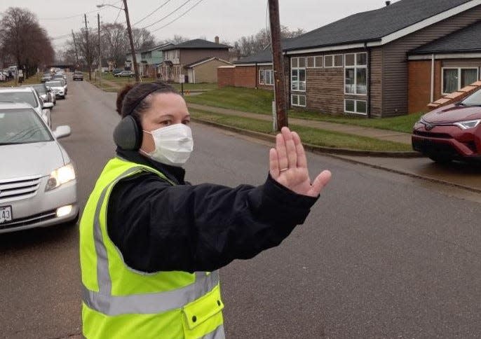 Bethany Perkowski, environmental health director at the Massillon Health Department, directs traffic Wednesday morning so motorists could safely enter the agency's parking lot for COVID-19 test kits.