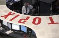 Employees of the Tokyo Stock Exchange (TSE) look at a monitor at the bourse at the TSE in Tokyo March 3, 2014. REUTERS/Issei Kato