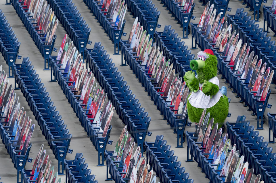 The Phillie Phanatic tries to cheer the team on while surrounded by the cutouts of fans in the seats during a baseball game against the New York Mets, Sunday, Aug. 16, 2020, in Philadelphia. The Phillies did their best to compensate for the cold, sterile atmosphere by putting out an array of cardboard cutouts in the stands. (AP Photo/Chris Szagola)