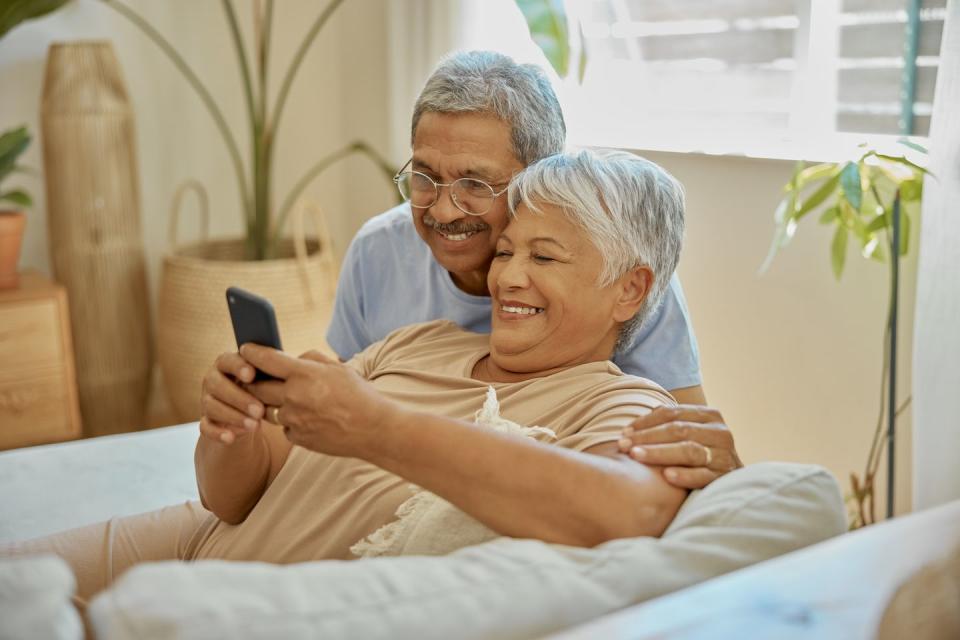 happy, couple embrace and reading from phone for communication, social media and news smile, affection and a senior man and woman on mobile app for notification, update and browsing retirement home