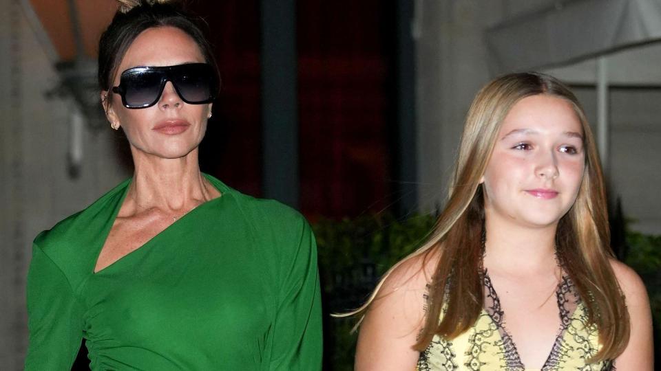 Victoria Beckham in a green dress holding hands with Harper Beckham