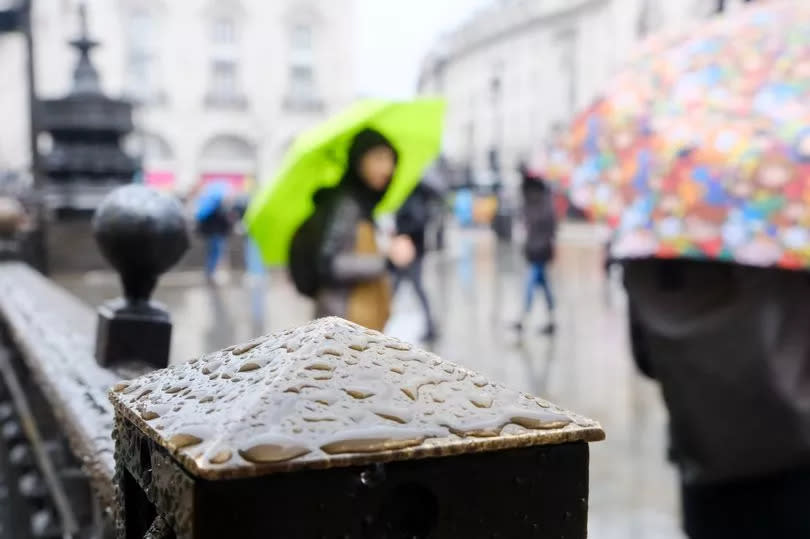 People hold umbrellas during a rainy day in London