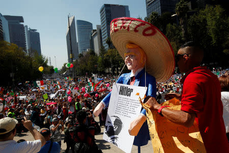 A man holds an effigy of U.S. President Donald Trump wearing a Mexican hat during a march to protest against Trump's proposed border wall and to call for unity, in Mexico City, Mexico, February 12, 2017. REUTERS/Jose Luis Gonzalez