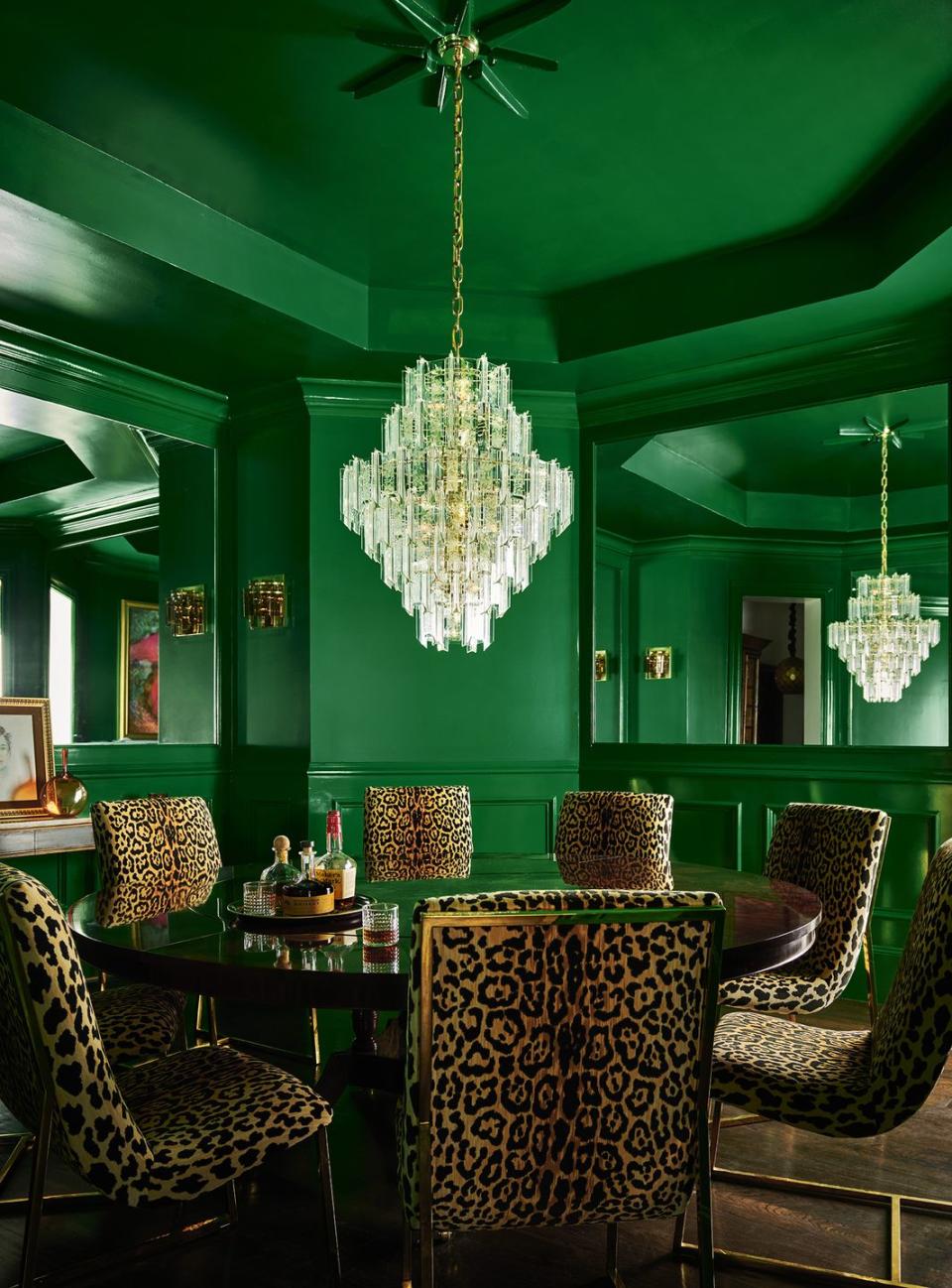 a green dining room with a round table, surrounded by chairs in an animal print fabric