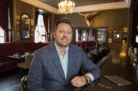 In this Feb. 11, 2020, photo, Brent Frederick, founder of Jester Concepts, a restaurant group in Minneapolis poses at P.S. Steak. Frederick puts a 3% voluntary surcharge on guest checks to help pay for health insurance and mental health services and says almost all guests agree to pay it. (AP Photo/Andy Clayton-King)