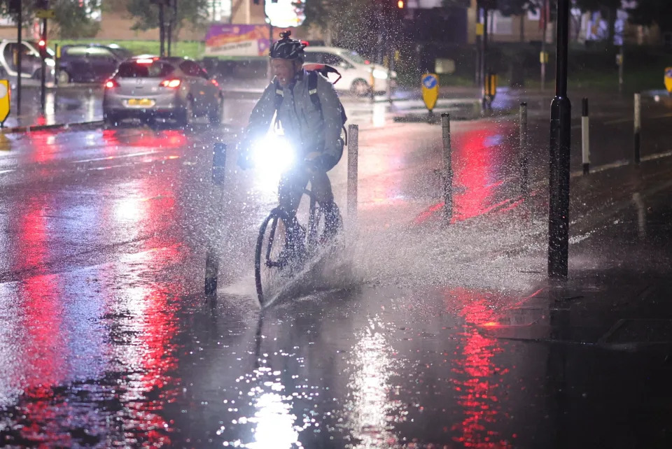 Cyclists attempt to navigate a section of flooded road in Colliers Wood (George Cracknell Wright)