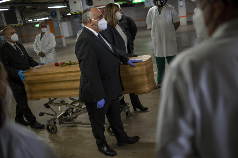Mortuary service workers carry the coffin of the last COVID-19 victim stored at an underground parking garage that was turned into a morgue, at the Collserola funeral home in Barcelona, Spain. May 17, 2020. A funeral home in Barcelona has closed a temporary morgue it had set up inside its parking garage to keep the victims of the Spanish city's coronavirus outbreak. The last coffin was removed and buried on Sunday. In 53 days of use, the temporary morgue has held more than 3,200 bodies. (AP Photo/Emilio Morenatti)