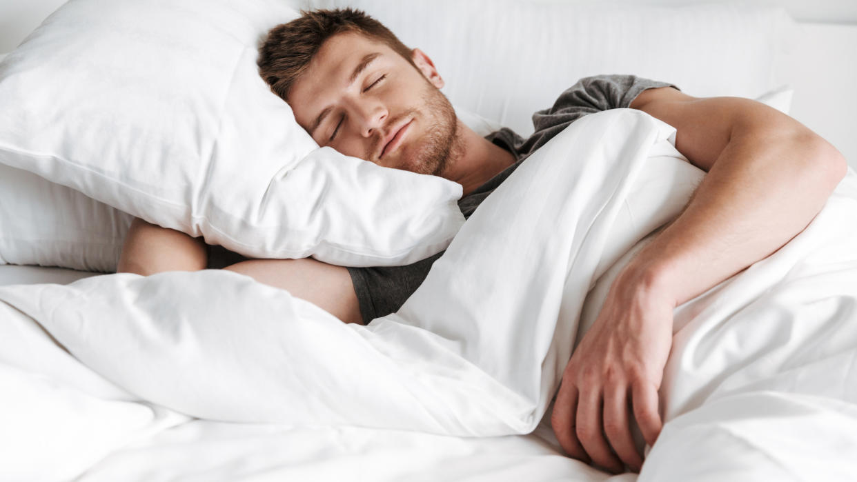  4 7 8 sleep method: A man with dark hair sleeps on his side covered by a white comforter. 