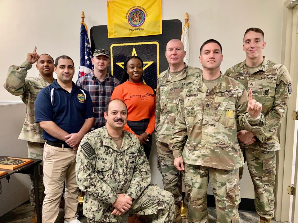 From left to right: Staff Sgt. Jeffery Robinson, (Army) Petty Officer 2nd Class Firas Warrad (Navy), Staff Sgt. Michael Pendleton (Army), Chief Charles Poplin (kneeling; Navy), Staff Sgt. Chanel Unanka (Army), Staff Sgt. Daniel Dragomirescu (Army), Sgt. 1st Class David Rodriguez (Army) and Sgt. Nicholas Rhode (Army) unite at the recruiting office on Pensacola Street. They have a heavy interest in the Army-Navy Game.