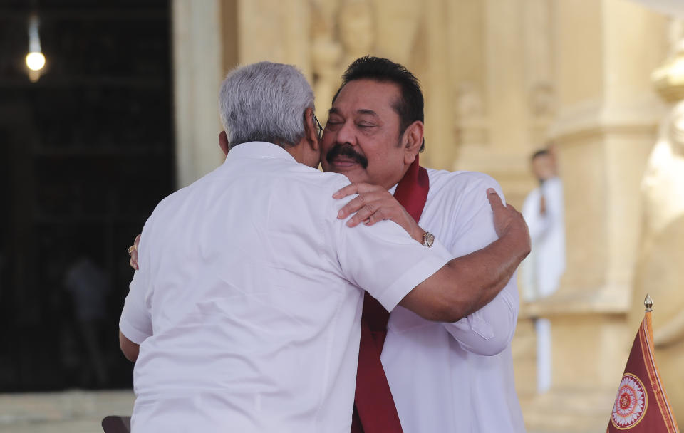 Sri Lanka’s former President Mahinda Rajapaksa, face to camera embraces his younger brother, President Gotabaya Rajapaksa, after being sworn in as the prime minister at Kelaniya Royal Buddhist temple in Colombo, Sri Lanka, Sunday, Aug. 9, 2020. (AP Photo/Eranga Jayawardena)