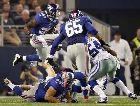 New York Giants running back David Wilson (22) hurdles fullback Henry Hynoski (45) as offensive tackle Will Beatty (65) blocks and Dallas Cowboys linebacker Bruce Carter (54) moves in for the tackle during the first half of their NFL football game in Arlington, Texas September 8, 2013. REUTERS/Mike Stone