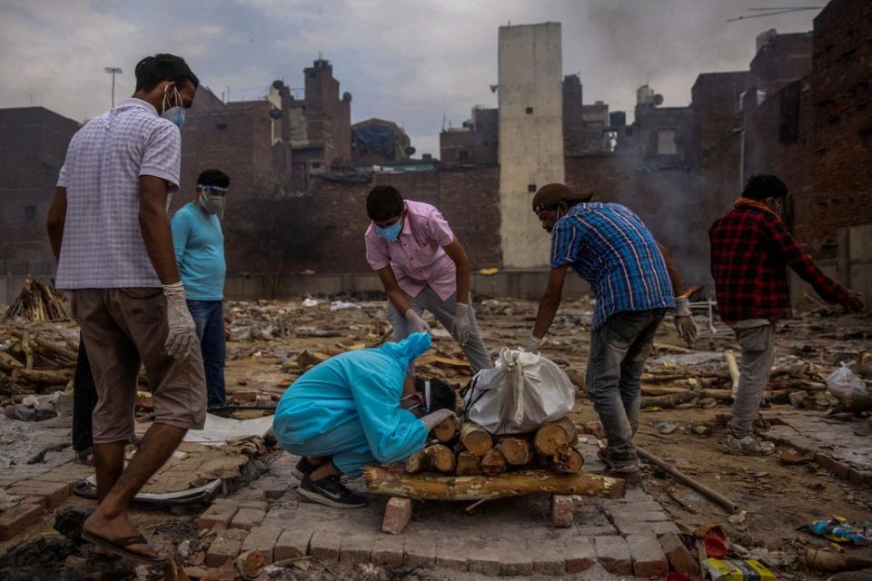 Pranav Mishra, 19, kneels toward the body of his mother Mamta Mishra who died aged 45 from coronavirus, ahead of her cremation in New Delhi on 4 May 2021 (Reuters/Danish Siddiqui)