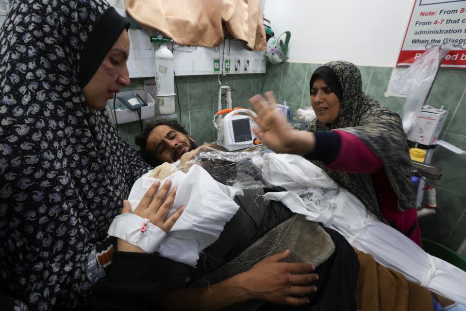 加薩拉法市18日遭以色列空襲，一名父親受傷躺在醫院，其母親和妻子抱著兒子的屍體給他看。路透社
