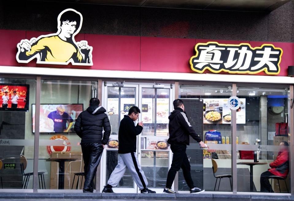 People walk past the restaurant Real Kung Fu, or Zhen Gongfu in Mandarin, run by fast food chain Kungfu Catering Management, in Beijing on December 26, 2019. - Shannon Lee's Bruce Lee Enterprises is suing restaurant chain Kungfu Catering Management of having used her late father's image for 15 years in a logo without paying intellectual property rights. (Photo by Noel CELIS / AFP) (Photo by NOEL CELIS/AFP via Getty Images)