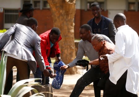 Bystanders assist a woman injured during clashes after police banned planned protests over austerity and rising living costs called by the opposition Movement for Democratic Change (MDC) party in Harare