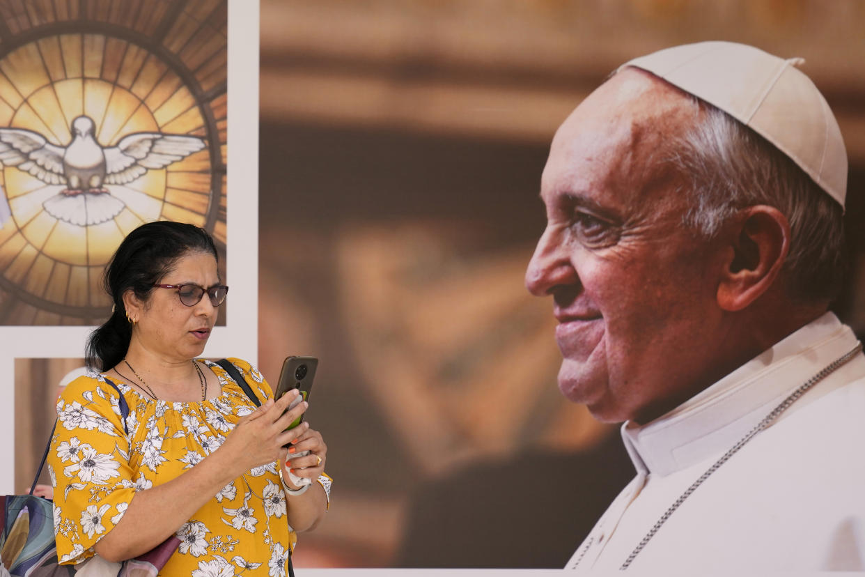 A woman speaks on her mobile phone, as she stands in front of a portrait of Pope Francis, at Sacred Heart church, in Manama, Bahrain, Wednesday, Nov. 2, 2022. Pope Francis is making the November 3-6 visit to participate in a government-sponsored conference on East-West dialogue and to minister to Bahrain's tiny Catholic community, part of his effort to pursue dialogue with the Muslim world. (AP Photo/Hussein Malla)