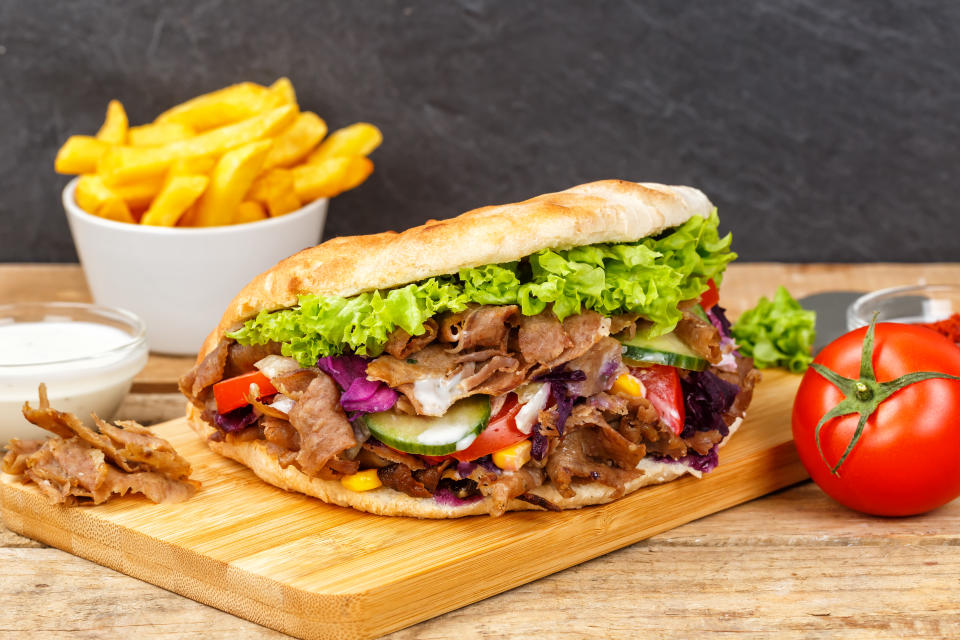 Döner Kebab Doner Kebap fast food meal in flatbread with french fries on a wooden board