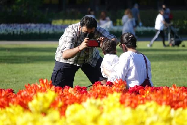 People take photos near the tulips at Ottawa's Commissioners Park Ottawa on May 13, 2021, during the third wave of the COVID-19 pandemic.