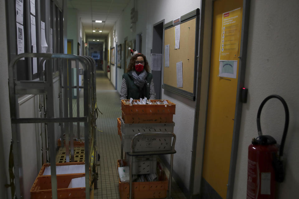 A postal worker brings a trolley of envelopes addressed to "Pere Noel" - Father Christmas in French - in Libourne, southwest France, Monday, Nov. 23, 2020. Letters pouring by the tens of thousands into Santa's mailbox offer a glimpse into the worries and hopes of children awaiting a pandemic-hit Christmas. Along with usual pleas for toys and gadgets, kids are also mailing requests for vaccines, for visits from grandparents, for life to return to the way it was. The office estimates that one letter in three mentions the pandemic. (AP Photo/Francois Mori)