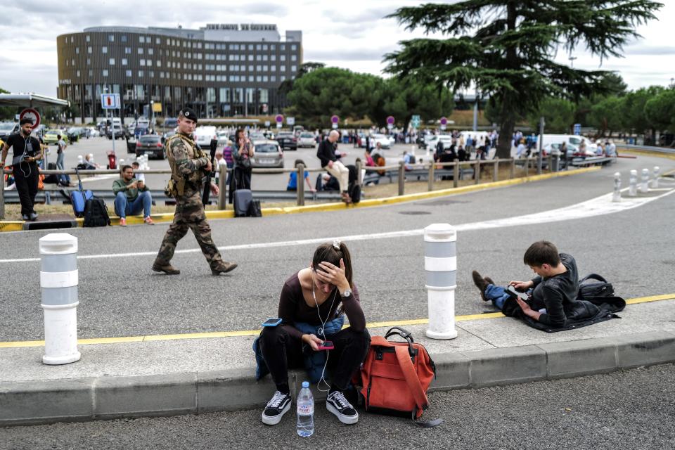 Passengers wait as a French soldier patrols outside the Toulouse-Blagnac Airport in Blagnac, southwestern France, on October 18, 2023.