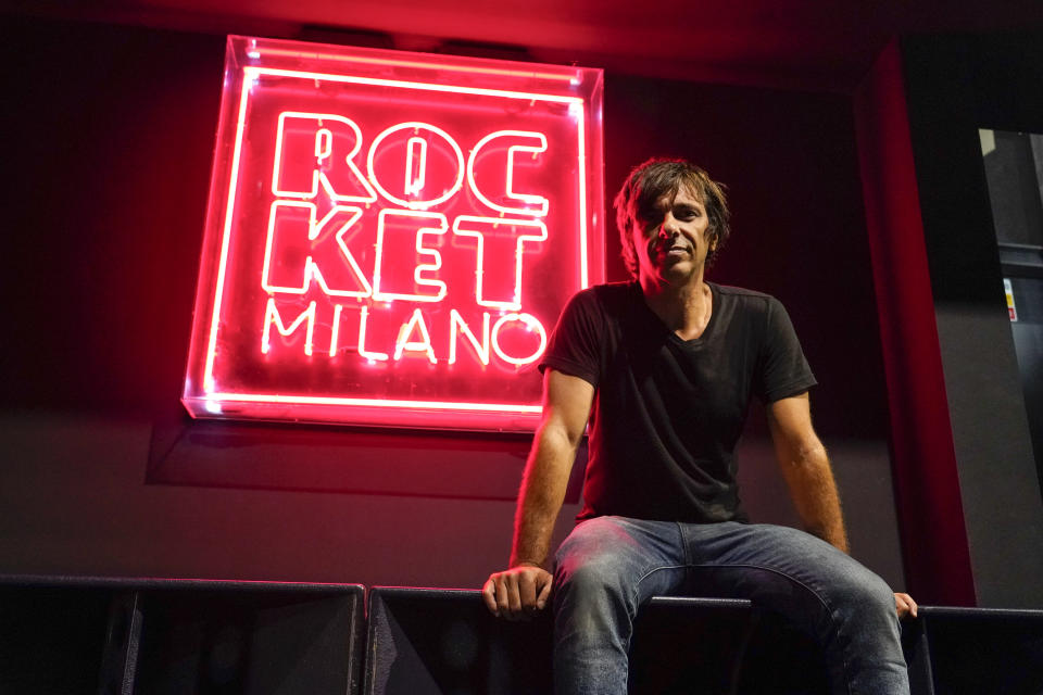 Massimiliano Ruffolo, owner of the Rocket Club sits next to a neon sign inside the empty venue, in Milan, Saturday, Sept. 25, 2021, more than 19 months after the government shut down Milan’s club scene after the first local transmission of coronavirus in the West was detected just an hour away. With Italy’s vaccination campaign now advanced, the government has finally given the green light for nightclubs to reopen this weekend at 50% capacity indoors, and 70% in the open air. (AP Photo/Alberto Pezzali)
