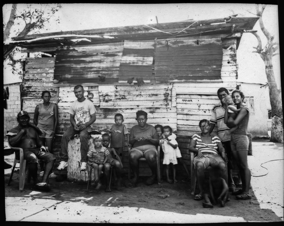 The Elizalzabal and Silva families, who fish for a living, pose for a group portrait outside one of their family's homes, on the shore of oil-contaminated Lake Maracaibo in Cabimas, Venezuela, July 3, 2019. (AP Photo/Rodrigo Abd)