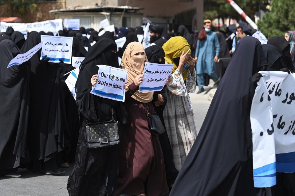 Veiled women hold banners and placards while marching during a pro-Taliban rally outside the Shaheed Rabbani Education University in Kabul on September 11, 2021.