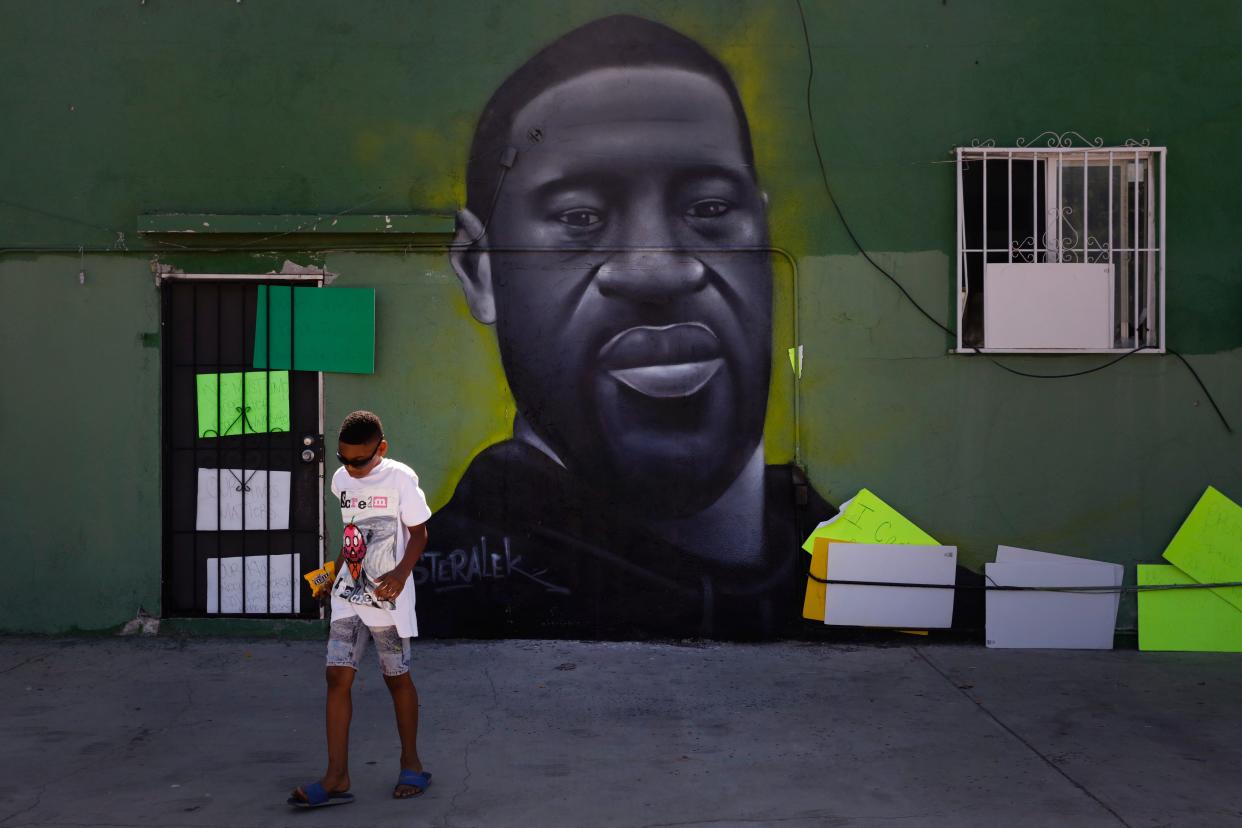 Benjamin Jackson III, 10, walks past a mural depicting George Floyd in the Watts neighborhood of Los Angeles in 2020.