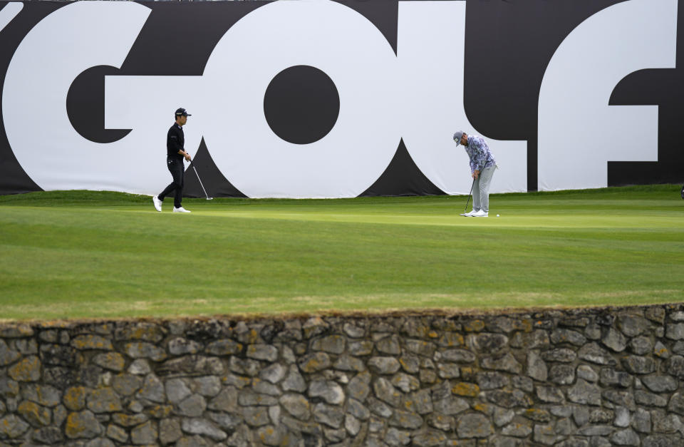 Kevin Na of the United States, left, stands on the 18th green during the first round of the inaugural LIV Golf Invitational at the Centurion Club in St. Albans, England, Thursday, June 9, 2022. The first LIV Golf Invitational, which offers $25 million in prize money, is taking place outside London starting Thursday. (AP Photo/Alastair Grant)