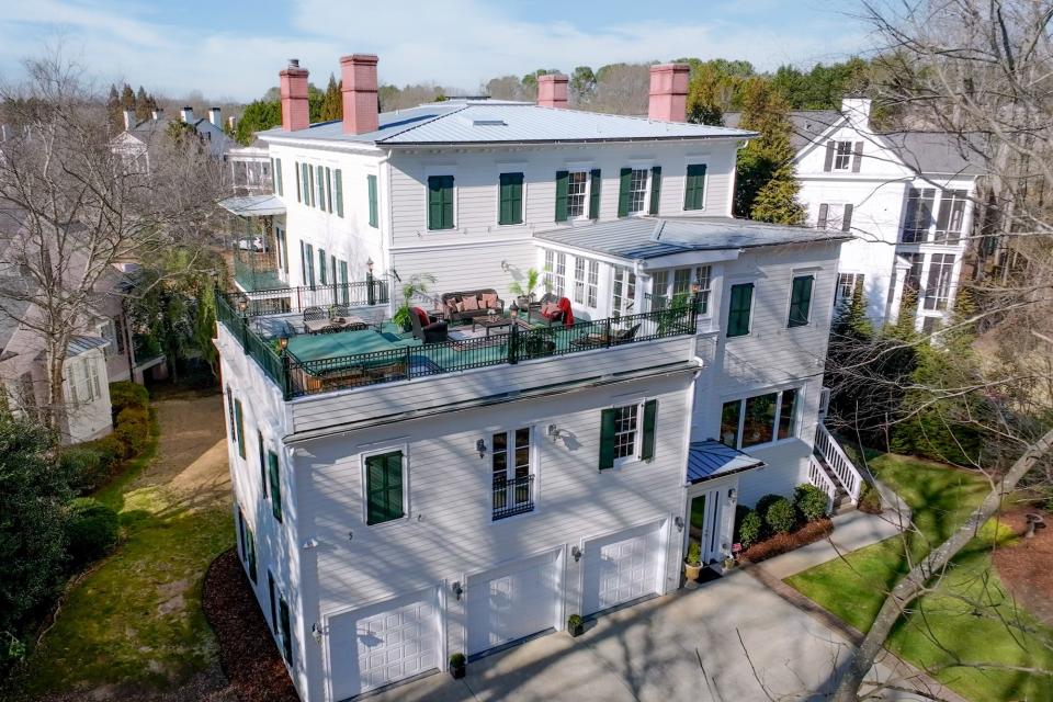 A large, white house with a three-car garage and a raised patio.