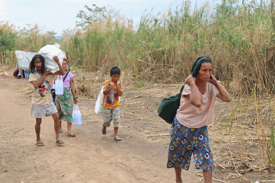 FILE - Displaced people from Myanmar carry donated lunch boxes to their tents along the Thai side of the Moei River in Mae Sot, Thailand on Feb. 5, 2022. The U.N.’s humanitarian relief agency said in a report updated through May 2022, that the number of displaced people in strife-torn Myanmar has for the first time exceeded 1 million, with well over half the total losing their homes after a military takeover last year. (AP Photo, File)