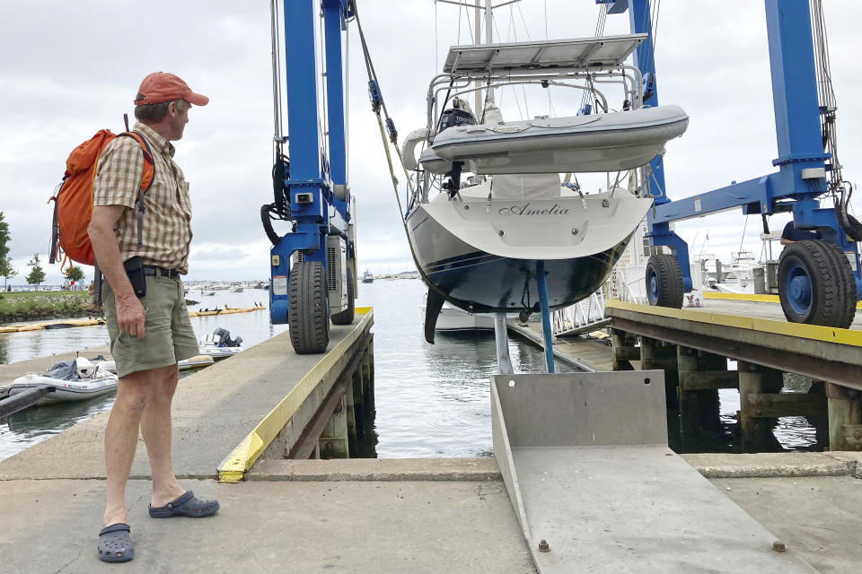 Robin Berthet, of Sheffield, Mass., watches as his sailboat is hauled out of the water onto dry land in advance of an expected storm, Friday Aug. 20, 2021, in Plymouth, Mass. New Englanders, bracing for their first direct hit by a hurricane in 30 years, are taking precautions as Tropical Storm Henri barrels toward the southern New England coast. (AP Photo/Phil Marcelo)