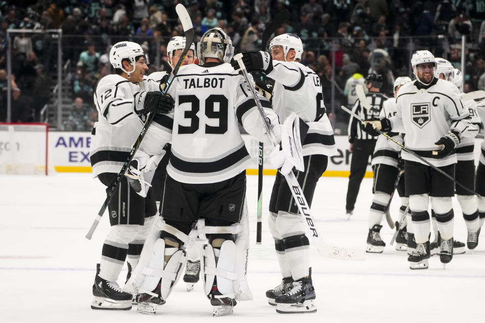 Los Angeles Kings left wing Trevor Moore (12) and center Trevor Lewis (61) skate over to greet goaltender Cam Talbot (39) after winning a shootout against the Seattle Kraken in an NHL hockey game Saturday, Dec. 16, 2023, in Seattle. (AP Photo/Lindsey Wasson)