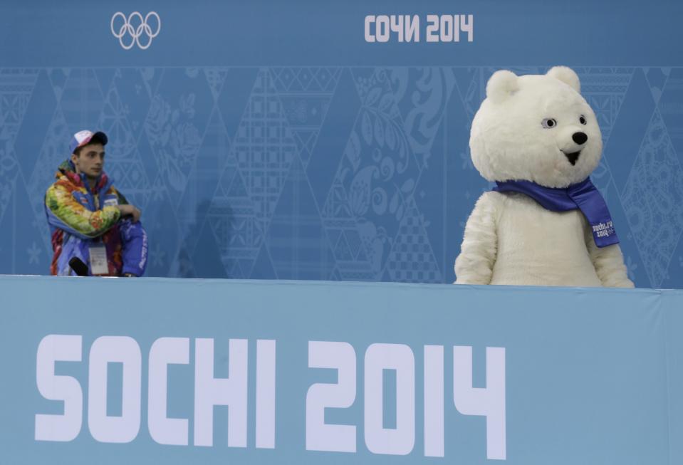 A volunteer looks at the polar bear mascot of the 2014 Sochi Olympics Games at the Ice Cube Curling Centre in Sochi February 11, 2014. REUTERS/Ints Kalnins (RUSSIA - Tags: SPORT OLYMPICS SPORT CURLING)