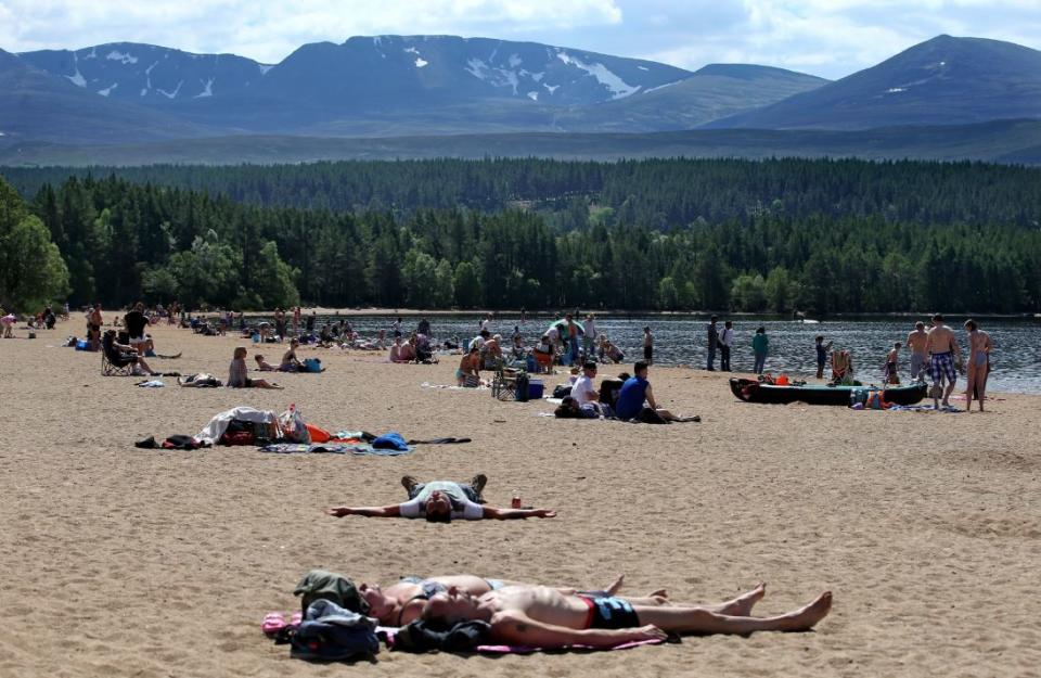 Bathers enjoy the warm weather despite snow still on the Scottish Cairngorms in May this year (PA)