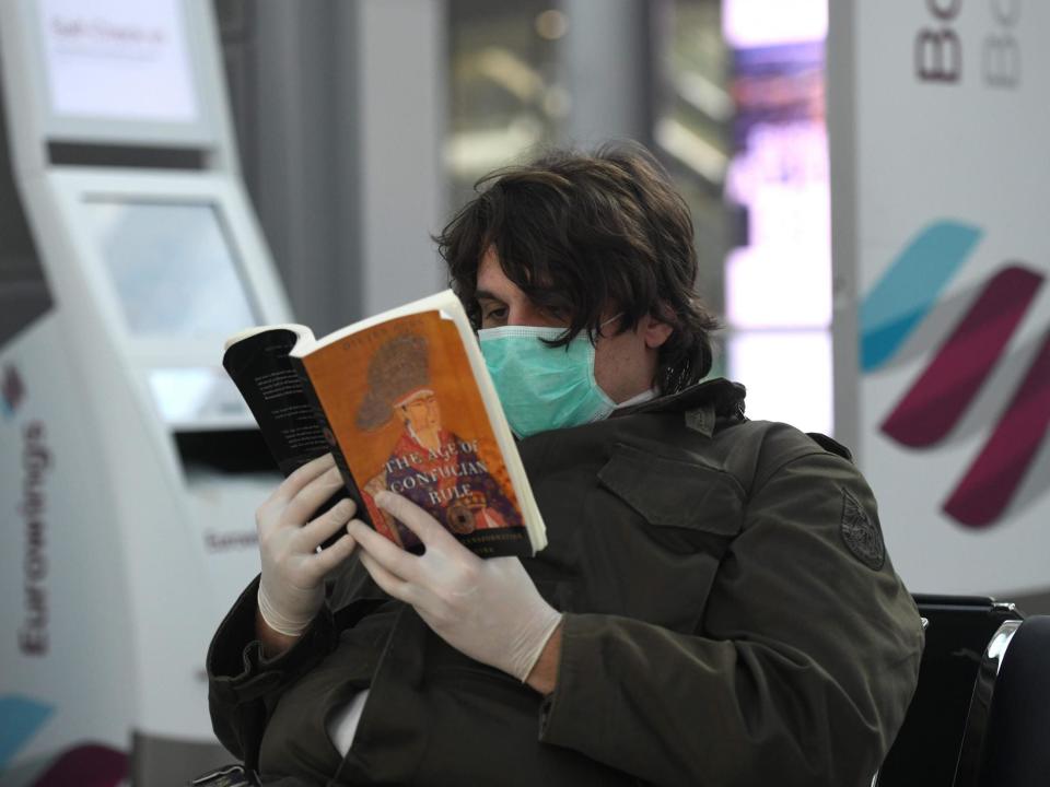 A passenger from Greece with a protective mask reads a book at Duesseldorf's airport: AFP/Getty