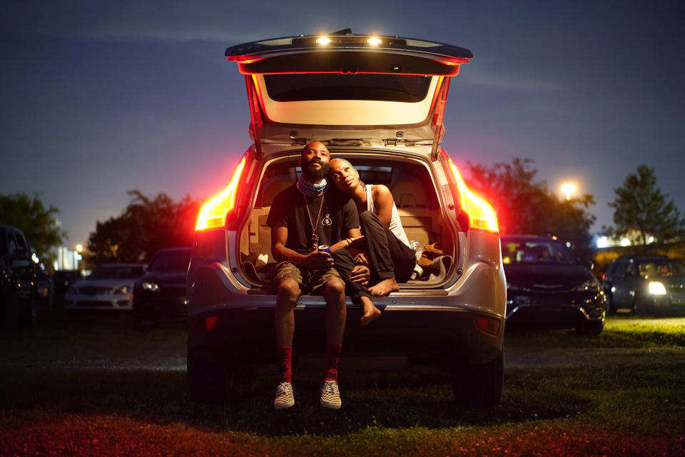 Kene Daniels, right, and Amman Raheem watch a documentary called "Rebuilding Black Wall Street," during a drive-in screening of documentaries during centennial commemorations of the Tulsa Race Massacre, Wednesday, May 26, 2021, in Tulsa, Okla. (AP Photo/John Locher)