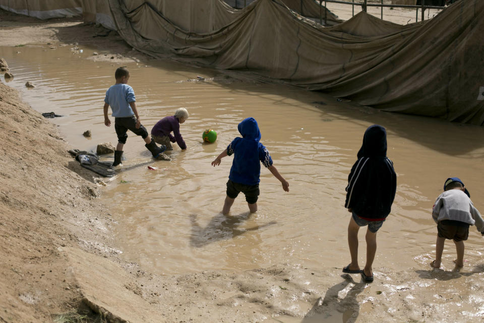 In this March 31, 2019, photo, children play in a mud puddle in the section for foreign families at Al-Hol camp in Hassakeh province, Syria. Some women who travelled across the world to join the Islamic State group’s “caliphate” are pleading to return home, expressing regret and saying they were deceived by the militants’ propaganda. Their pleas point to the thorny issues of what to do with the tens of thousands of former IS members left after the fall of the militants. Governments have been reluctant to allow their nationals back. (AP Photo/Maya Alleruzzo)