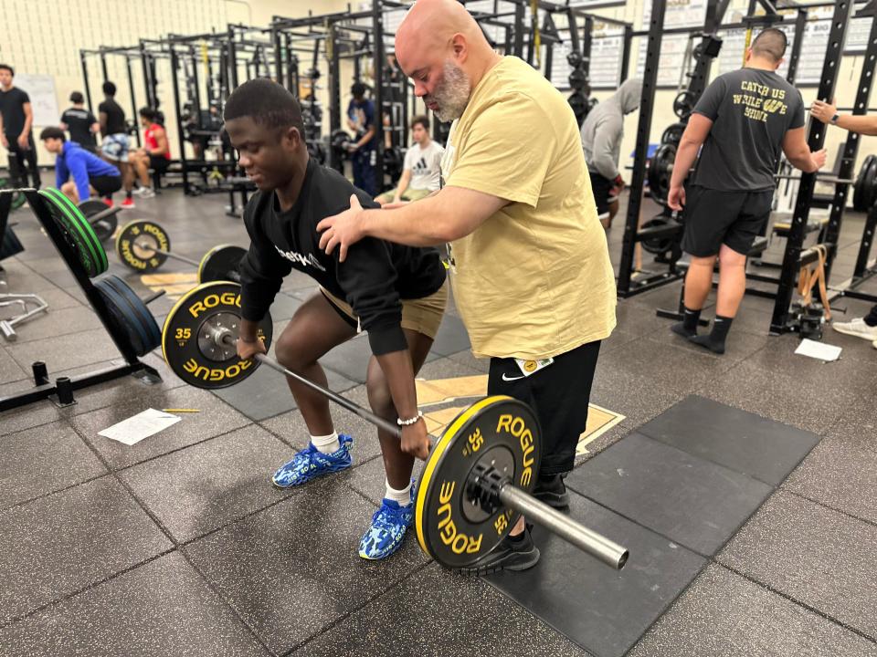 Strength-and-conditioning coach Jerry Clark assists a student athlete in the weight room at Warren Central High School in Indianapolis. Clark has been a strength-and-conditioning coach since 2006 thanks to his father, who introduced him to bodybuilding.