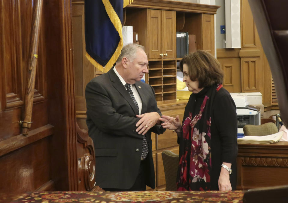 Kansas Senate Majority Leader Jim Denning, left, R-Overland Park, confers with state Rep. Kathy Wolfe Moore, D-Kansas City, on the far end of the House speaker's raised dais during a long break in the House's session, Friday night, May 3, 2019, at the Statehouse in Topeka, Kansas. Medicaid expansion supporters in the House, including Wolfe Moore, are blocking a proposed state budget to get a vote on expansion in the Senate, where Denning wants to wait until next year. (AP Photo/John Hanna)