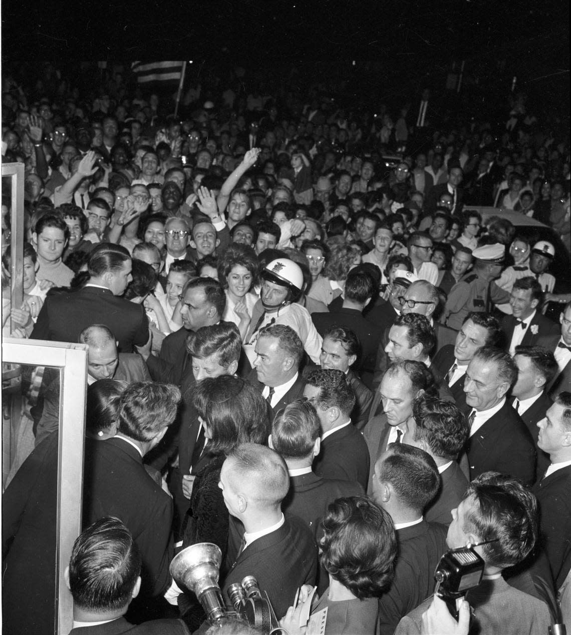 President John F. Kennedy and wife Jackie, surrounded by a crowd and followed by bodyguard Clint Hill and Vice President Lyndon Johnson, enter Hotel Texas in downtown Fort Worth on Nov. 21, 1963.