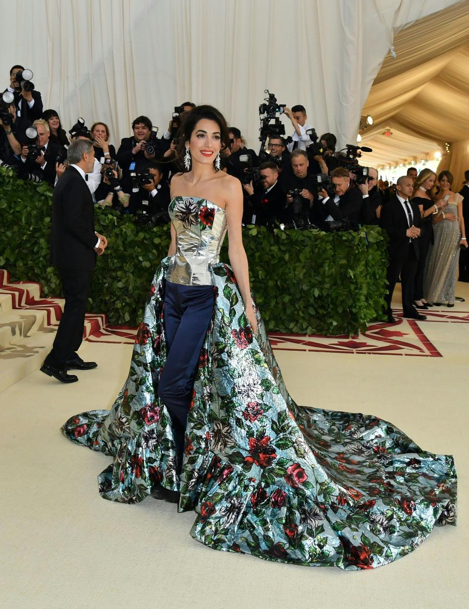 Amal posing in a gown/pants ensemble on the red carpet