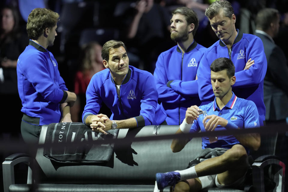 Team Europe's Roger Federer, second left looks up as he stands behind teammate Team Europe's Novak Djokovic, who is taking a drink at a change of ends as he plays against Team Wold'sFelix Auger-Allassime during their singles tennis match on third day of the Laver Cup tennis tournament at the O2 arena in London, Sunday, Sept. 25, 2022. (AP Photo/Kin Cheung)