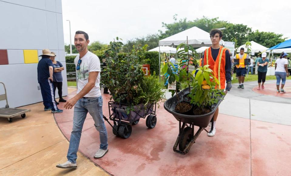 Amida Frey, left, pulls a cart of free trees she received during the Miami-Dade County Adopt-a-Tree event outside the Dennis C. Moss Cultural Arts Center on Saturday, Sept. 23, 2023, in Cutler Bay, Florida.  more than 2,500 trees were available for adoption during the event, which drew long lines of attendees.